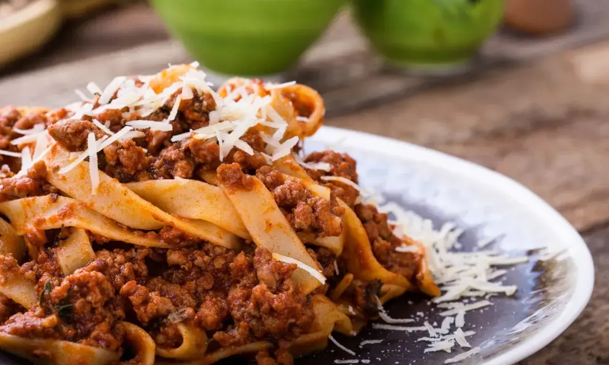 Pappardelle z bogatym sosem bolognese, idealne pytanie: jakie mięso do spaghetti? Posypane parmezanem.
