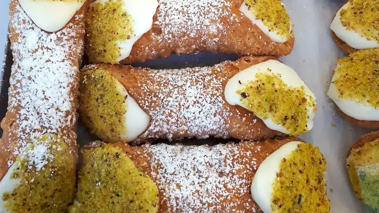 Chrupiące rurki z kremem, posypane cukrem pudrem i pistacjami, kuszą swoim wyglądem.