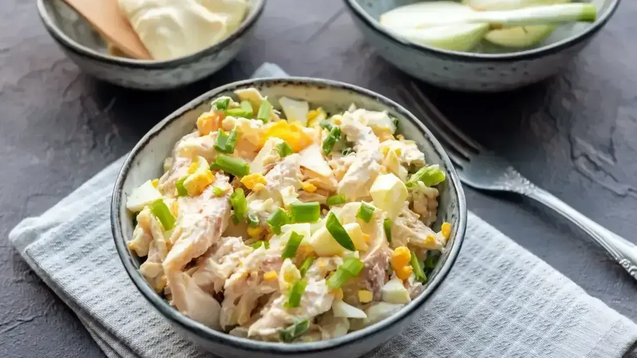 Pyszna sałatka z wędzonym kurczakiem, jajkiem i szczypiorkiem, polana majonezem. Idealna na szybki lunch.