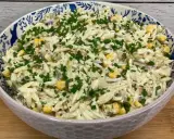 Pyszna sałatka z tuńczykiem, makaronem orzo, kukurydzą i szczypiorkiem, podana w ozdobnej misce.