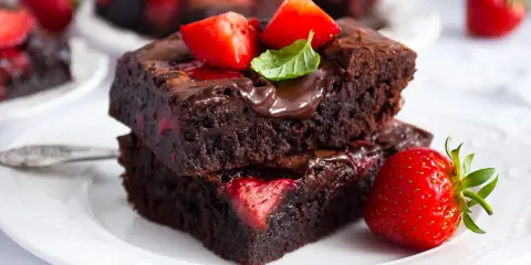 Pyszne brownie z truskawkami, polane czekoladą i ozdobione świeżymi owocami. Idealne na deser!