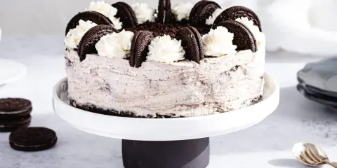 Pyszny sernik oreo na zimno, udekorowany bitą śmietaną i ciasteczkami. Idealny deser na upalne dni.