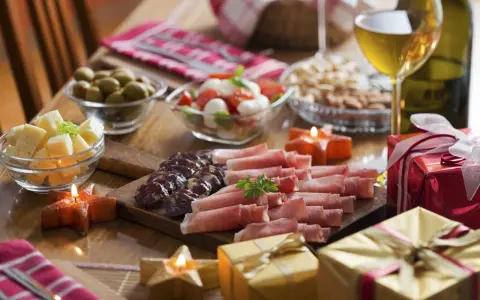 Eleganckie menu na sylwestra w domu: wędliny, sery, oliwki, pomidorki z mozzarellą, orzechy, wino i prezenty.