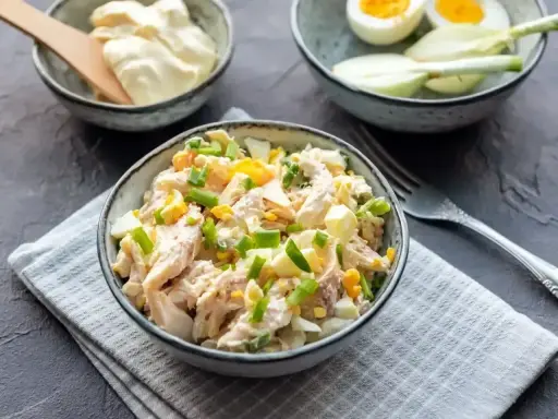 Pyszna sałatka z wędzonym kurczakiem, jajkiem i szczypiorkiem, polana majonezem. Idealna na szybki lunch.