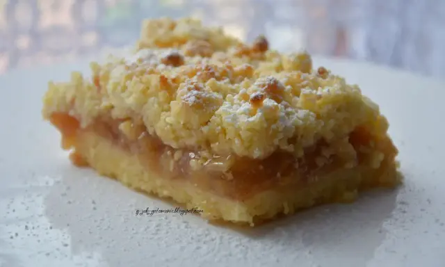 Pyszna tarta z jabłkami, posypana cukrem pudrem, kusi chrupiącą kruszonką i aromatycznym nadzieniem.