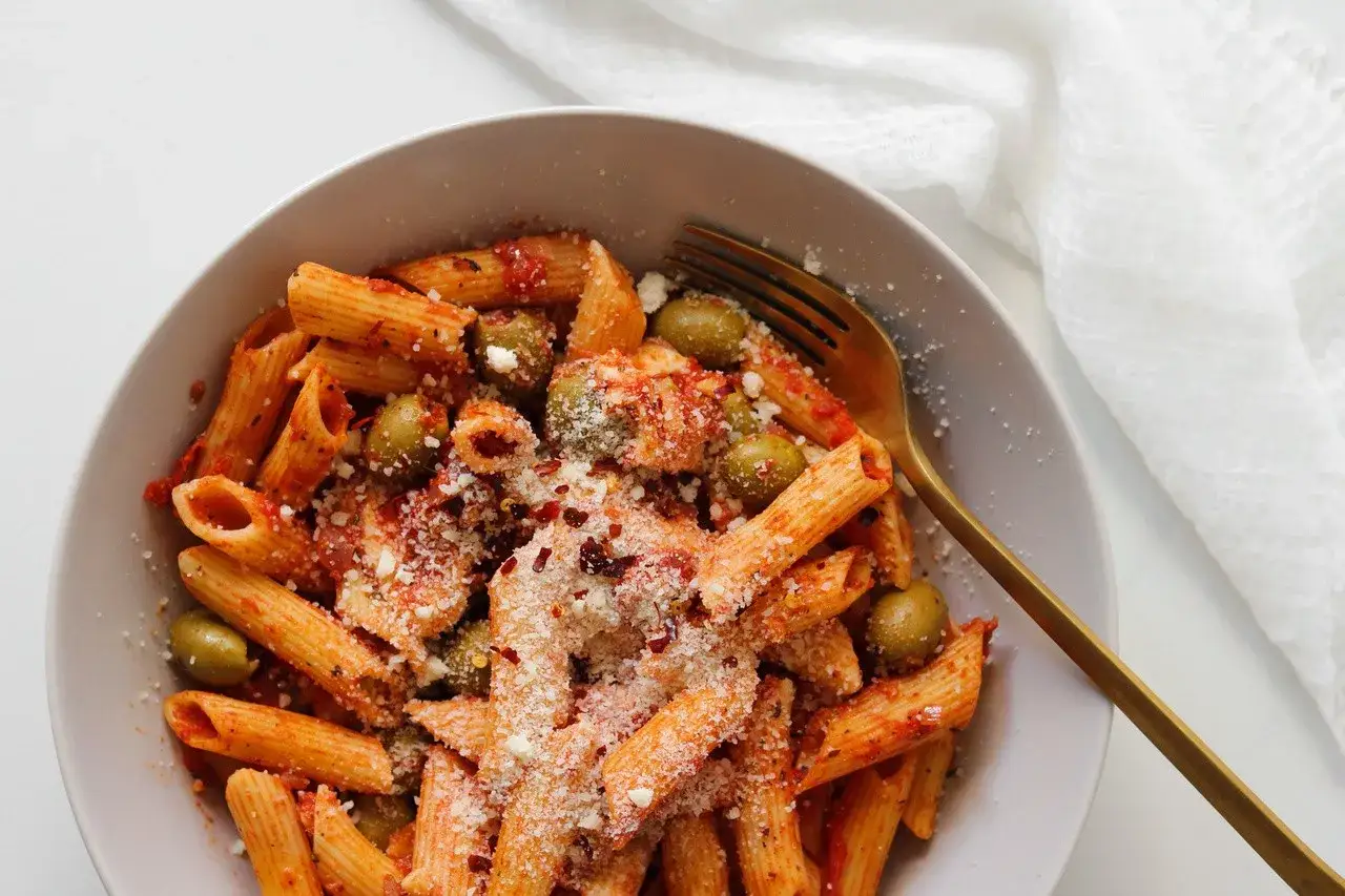 Penne z sosem pomidorowym, oliwkami i startą mozzarellą, posypane płatkami chili. Idealny makaron z mozzarellą na szybki obiad.