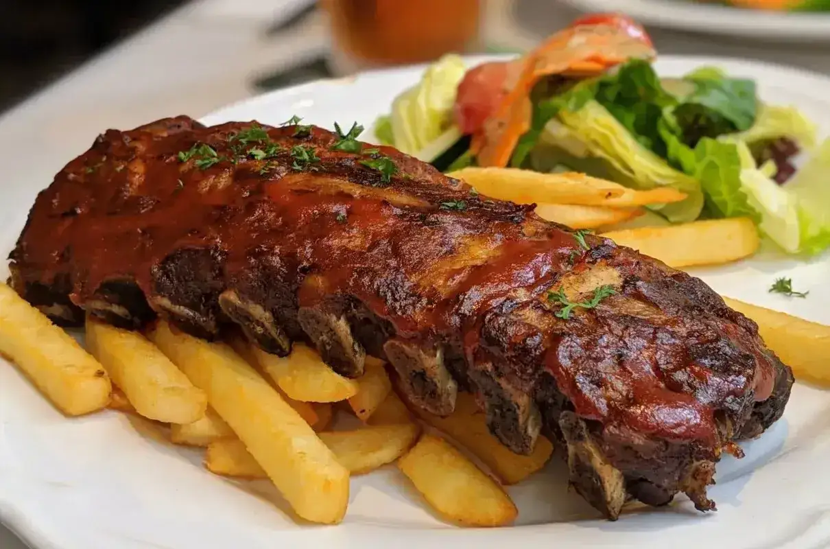 Soczyste żeberka w sosie BBQ, podane z chrupiącymi frytkami i świeżą sałatką. Idealna marynata do żeberek sprawia, że mięso jest niezwykle aromatyczne.